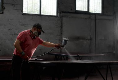 Metal yapıyı sprey silahla boyayan adam.