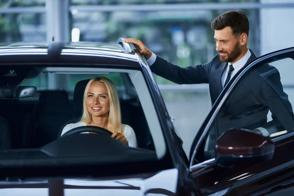 Mujer elegir un coche nuevo con la ayuda del vendedor —  Fotos de Stock