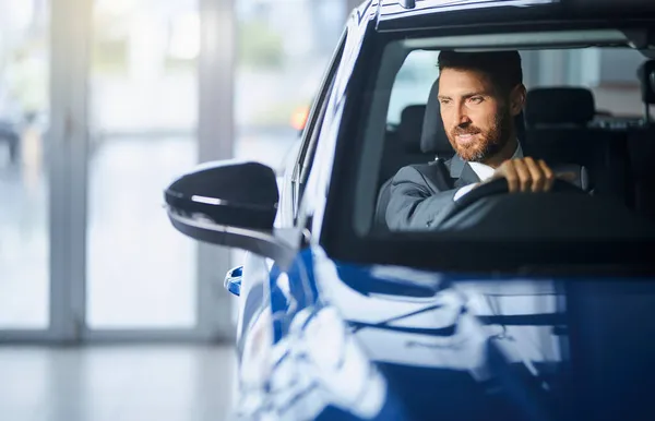 Hombre de negocios probando el coche en el salón de auto moderno —  Fotos de Stock