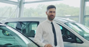 Otomobil kuaföründe dikilen ve gülümseyen bir adam.