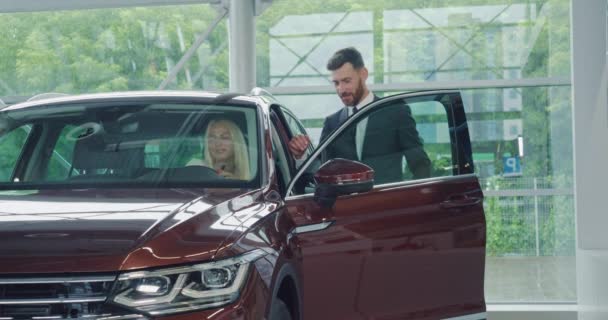 Salesman menunjukkan interior mobil modern untuk pembeli perempuan — Stok Video