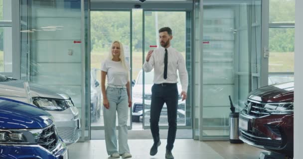Торговець допомагає жінці вибирати машину в салоні — стокове відео
