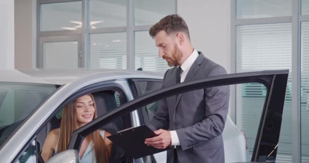 Car dealer showing female buyer new auto at salon — Stock Video