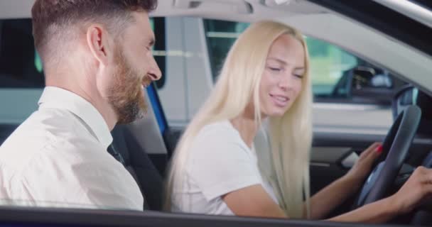 Försäljare sitter med kvinna i bilen och undersöker interiören — Stockvideo