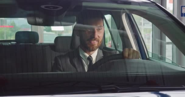 Man in stylish suit examining new car at modern salon — Stock Video