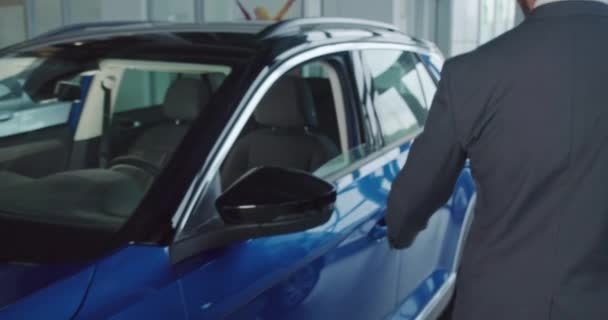Boldog üzletember tesztelés autó bemutatóteremben vásárlás előtt — Stock videók