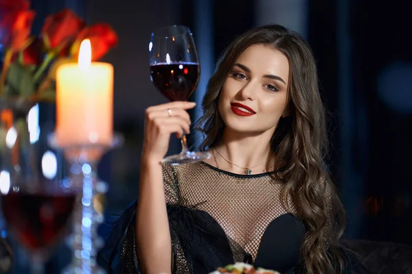 Atemberaubende Frau sitzt mit einem Glas Rotwein am Tisch — Stockfoto