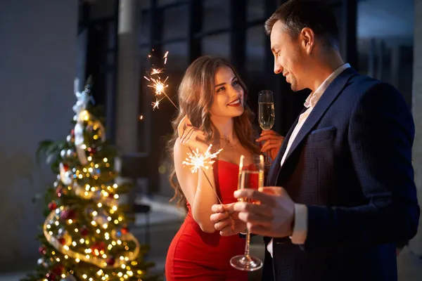 Casal encantador bebendo champanhe e usando sparklers — Fotografia de Stock