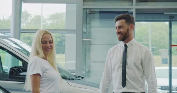 Salesman допомагає жіночому клієнту вибирати автомобіль у шоу-румі — стокове відео