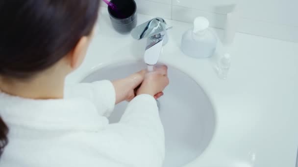 Junge Frau im Bademantel wäscht sich die Hände mit Seife — Stockvideo