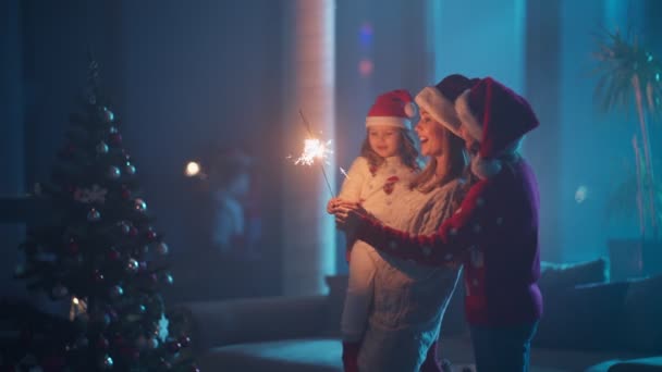 Matka i dzieci tańczą w pobliżu choinki z iskrami — Wideo stockowe