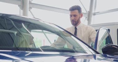 Satıcı, kadın müşteriye kuaförde araba seçmesinde yardım ediyor.