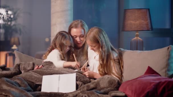 Kobieta z córkami rysunek w albumie podczas odpoczynku na kanapie — Wideo stockowe