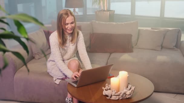 Mulher sentada no sofá e usando laptop para videochamada — Vídeo de Stock