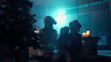Çocuklu bir kadın Noel ağacının yanında alkışlıyor ve şarkı söylüyor
