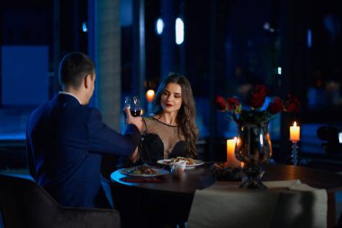 Genç çift evde buluşurken kırmızı şarapla kadeh kaldırıyor.