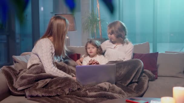 Nő ül a kanapén lányokkal és használja laptop — Stock videók
