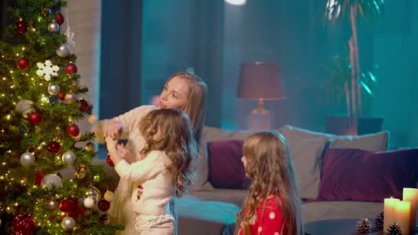 Aile Noel ağacını iki kızıyla süsleyen kadın. — Stok video