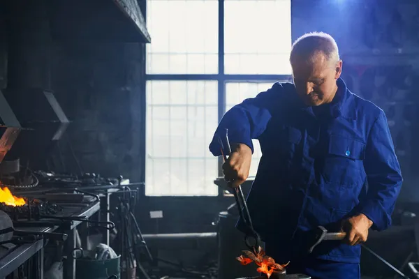 Muž v tmavě modré uniformě pracuje s kladivem a kleštěmi. — Stock fotografie