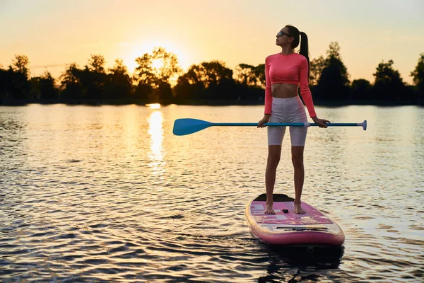 Aktive Frau schwimmt auf Surfbrett mit Paddel — Stockfoto