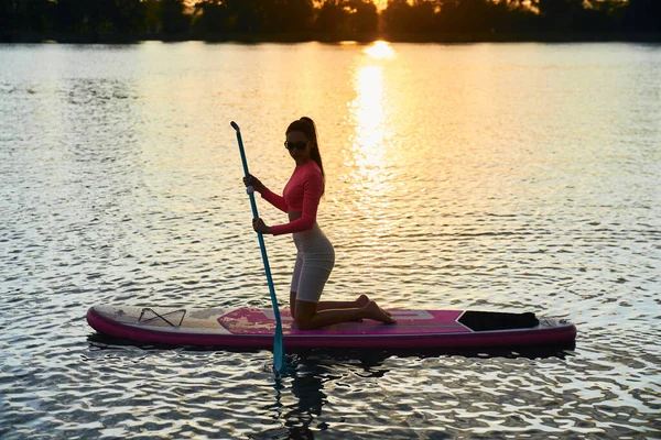 日落时年轻女子在船桨上冲浪很合适 — 图库照片