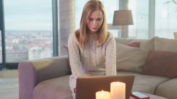 Kaukasische vrouw zitten op de bank en met behulp van laptop — Stockvideo