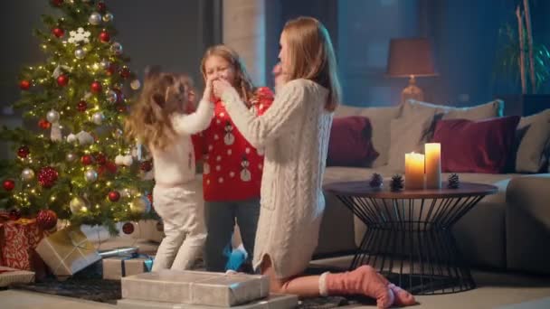 Mujer abrazando a sus hijas cerca del árbol de Navidad en casa — Vídeos de Stock