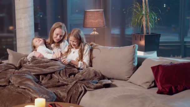 Schwestern malen in Album, während sie mit Mutter auf Sofa liegen — Stockvideo