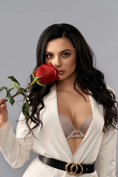 Frau hält rote Rose in der Nähe, während sie im Studio posiert — Stockfoto