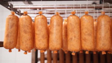 Kısa tütsülenmiş sosisler imalatta ipte sallanıyor..