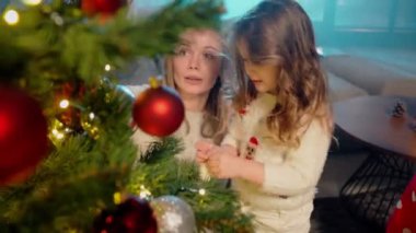 İki kız kardeş annemin Noel ağacını süslemesine yardım ediyor.