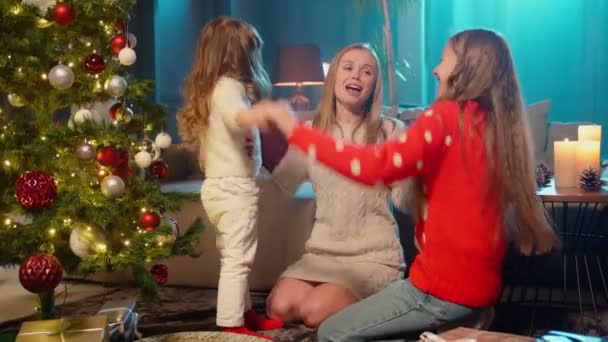 Anya játszik két lányával a karácsonyfa közelében. — Stock videók