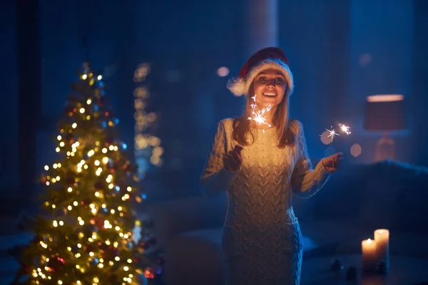 Glimlachende dame met bangal lichten staan in de buurt van kerstboom — Stockfoto