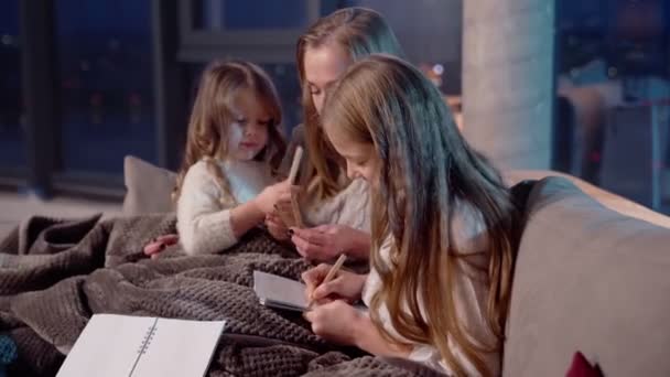 Hermanas sentadas con la madre en el sofá y pintando en el álbum — Vídeos de Stock