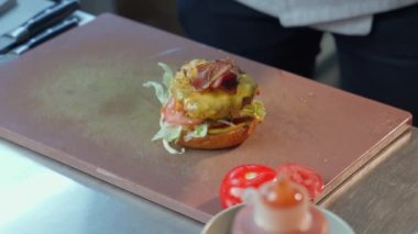 Aşçı mutfakta lezzetli bir burger pişiriyor. 