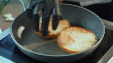 Eldivenli şefin kapısına yaklaşıp tavada hamburgerin pişmesini sağlayın.