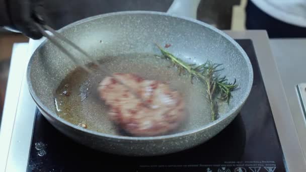 Dekat dengan koki menggoreng daging sapi pada minyak dengan rosemary — Stok Video