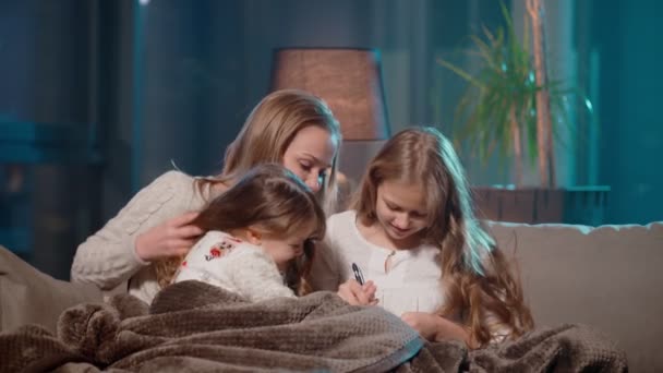 Anya a lányaival albumot fest a kanapéra — Stock videók