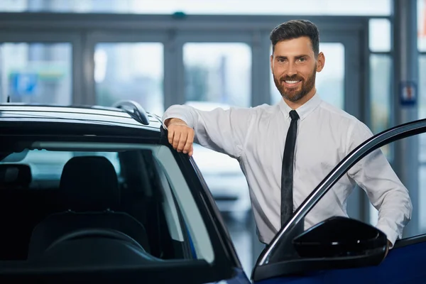 Feliz hombre de negocios eligiendo nuevo vehículo en la sala de exposición — Foto de Stock