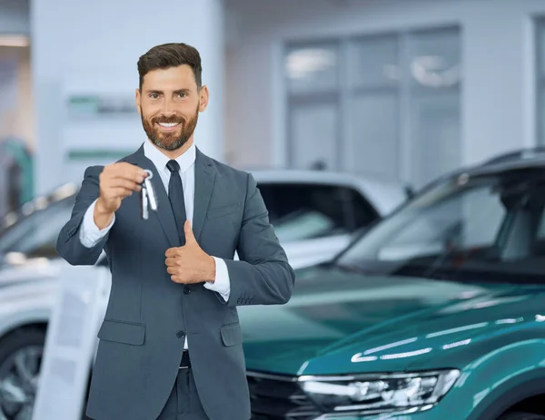 Hombre de traje mostrando el pulgar hacia arriba y sosteniendo las llaves de un coche nuevo —  Fotos de Stock