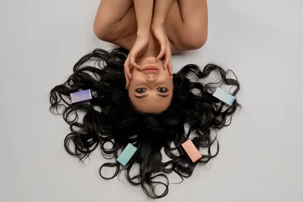 Tender woman with healthy dark wavy hair lying in studio — ストック写真