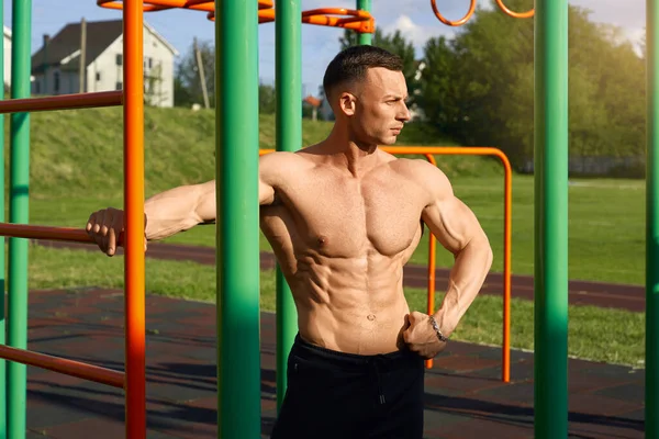 Male athlete with bare torso posting on sports ground — Stok fotoğraf