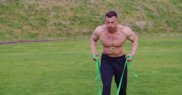 Sporty man training outdoors with rubber band — Video Stock