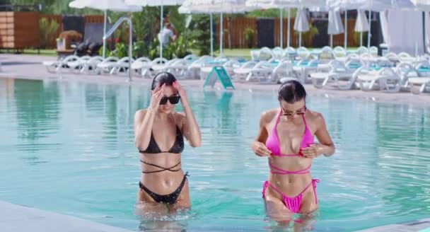 Två kaukasiska kvinnor i bikini som kliver ur poolen — Stockvideo