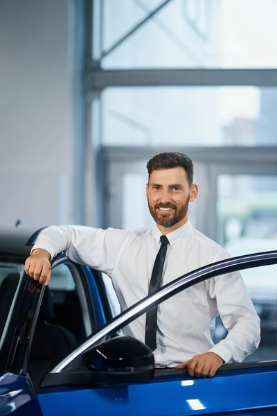 Affärsman stående på auto salong och leende på kameran — Stockfoto