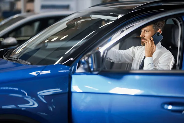 Hombre elegir el coche y hablar en el móvil en la sala de exposición —  Fotos de Stock