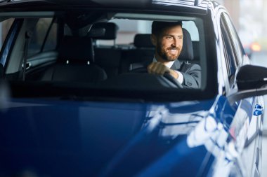 Modern kuaförde takım elbiseli gülümseyen adam arabayı test ediyor. 