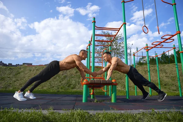 Dos hombres deportistas haciendo flexiones en el banco al aire libre — Foto de Stock