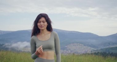 Yeşil doğada yürüyen spor elbiseli bir kadın.