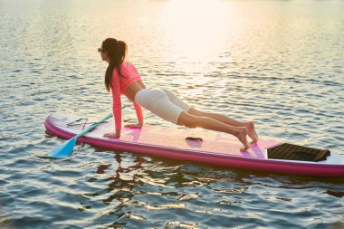 Kürek tahtasında tahta egzersizi yapan atletik bir kadın.